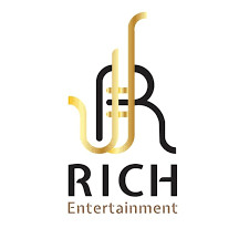 Monogram huruf R berwarna emas dan hitam membentuk garis melengkung menyerupai terompet; teks "RICH Entertainment" tercetak di bawahnya pada latar belakang putih bersih.
